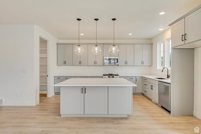 322 W Songbird Ln N Unit 24, Lindon, UT 84042 - kitchen featuring appliances with stainless steel finishes, a sink, a kitchen island, light countertops, and light wood-type flooring