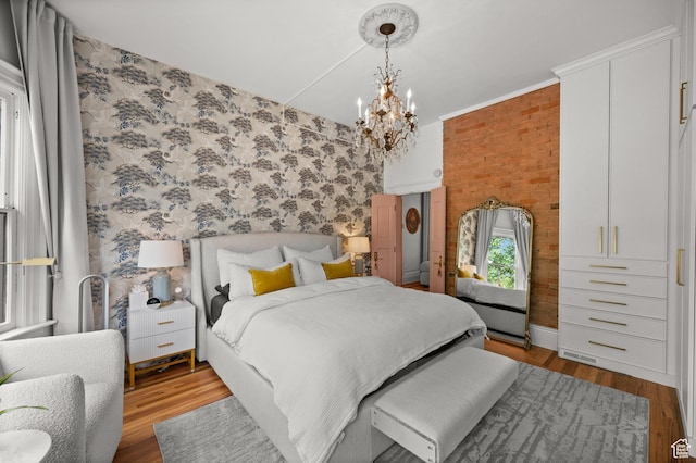 237 E 4th Ave N, Salt Lake City, UT 84103 - bedroom featuring light wood-type flooring, a chandelier, brick wall, and wallpapered walls