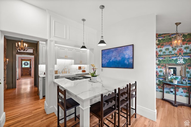237 E 4th Ave N, Salt Lake City, UT 84103 - kitchen featuring a chandelier, gas cooktop, light wood-type flooring, a kitchen breakfast bar, and light stone counters