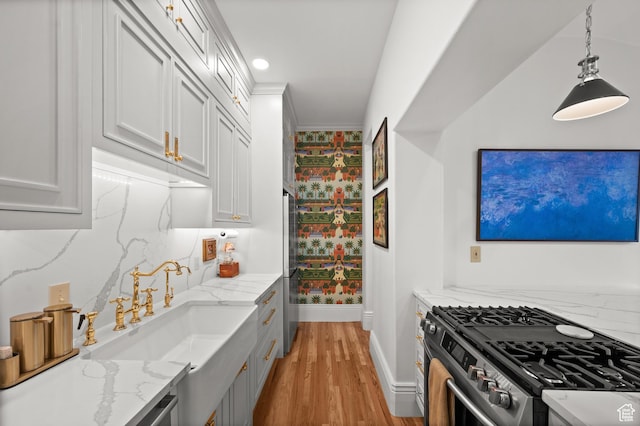 237 E 4th Ave N, Salt Lake City, UT 84103 - kitchen with stainless steel gas range oven, baseboards, light wood-style floors, light stone counters, and a sink
