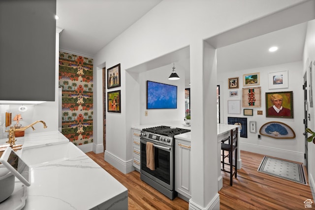 237 E 4th Ave N, Salt Lake City, UT 84103 - kitchen with gas stove, light wood finished floors, baseboards, light stone counters, and a breakfast bar area