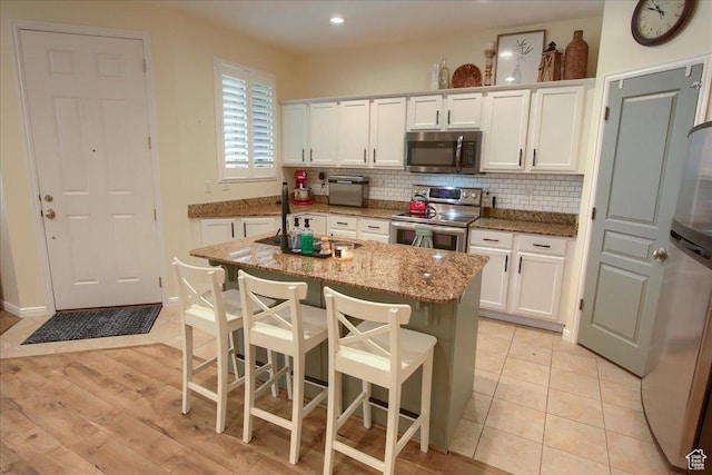 58 N 285 W, Centerville, UT 84014 - kitchen featuring appliances with stainless steel finishes, white cabinetry, tasteful backsplash, light stone countertops, and recessed lighting
