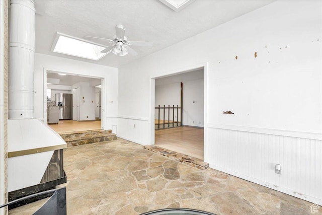 5424 S 850 E, South Ogden, UT 84405 - empty room with stone floors, a skylight, ceiling fan, and a wainscoted wall