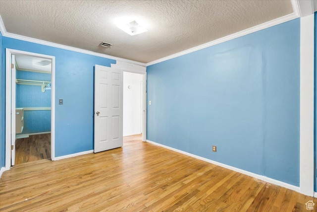 5424 S 850 E, South Ogden, UT 84405 - unfurnished bedroom with light wood-style floors, a textured ceiling, crown molding, a walk in closet, and baseboards
