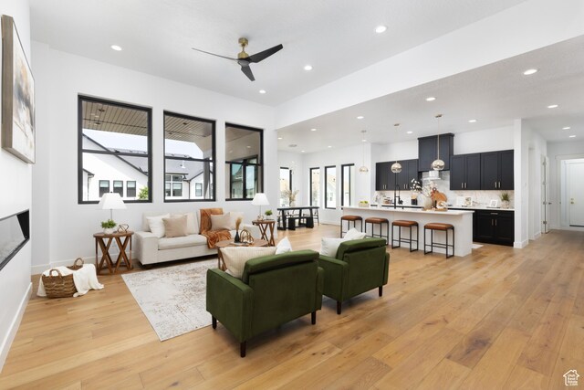 6552 W Timber Ranch Dr, Herriman, UT 84096 - living room featuring light wood finished floors, recessed lighting, ceiling fan, a glass covered fireplace, and baseboards