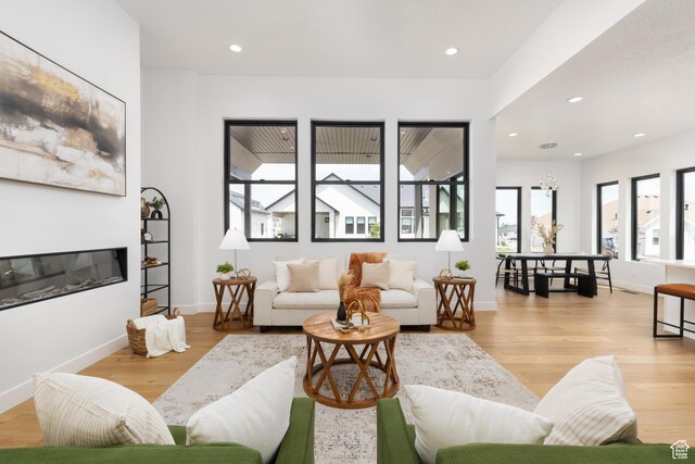 6552 W Timber Ranch Dr, Herriman, UT 84096 - living room featuring light wood-style floors, recessed lighting, baseboards, and a glass covered fireplace