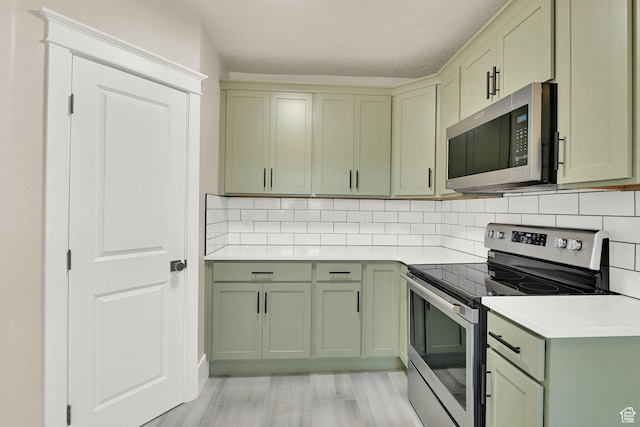 2654 Brinker Ave, Ogden, UT 84401 - kitchen with stainless steel appliances, green cabinetry, light countertops, backsplash, and light wood-style flooring