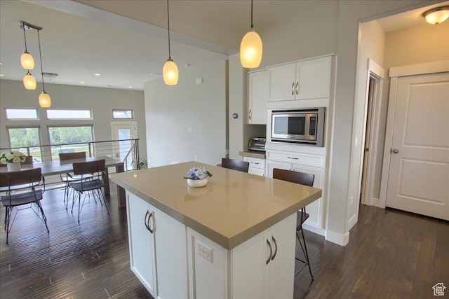 4508 W Kestrel Ridge Rd, South Jordan, UT 84009 - kitchen featuring stainless steel microwave, dark wood-style flooring, a center island, white cabinetry, and decorative light fixtures