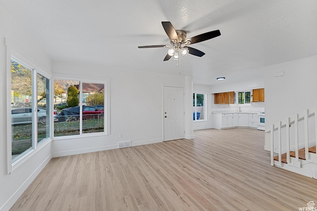 1167 29th St, Ogden, UT 84403 - unfurnished living room with light wood-style flooring, ceiling fan, baseboards, a sink, and stairway