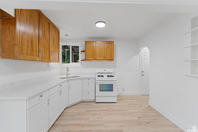 1167 29th St, Ogden, UT 84403 - kitchen featuring white gas range oven, open shelves, a sink, and arched walkways