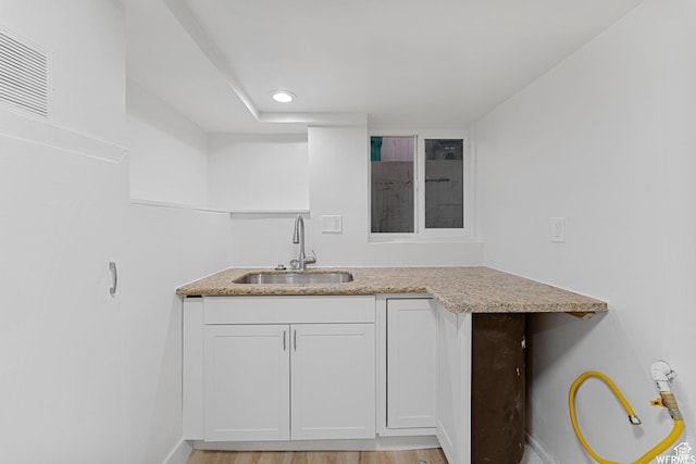 1167 29th St, Ogden, UT 84403 - kitchen featuring a sink, white cabinets, light stone counters, baseboards, and light wood-style floors