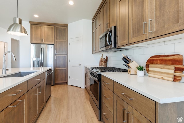 611 E 400 N, Providence, UT 84332 - kitchen featuring stainless steel appliances, light wood-style floors, a sink, decorative backsplash, and brown cabinets