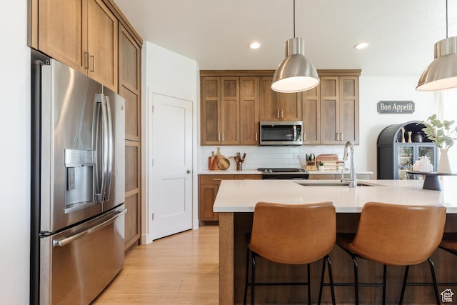 611 E 400 N, Providence, UT 84332 - kitchen featuring appliances with stainless steel finishes, a sink, light countertops, brown cabinets, and light wood finished floors