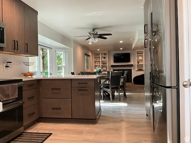 9574 S Equestrian Park Cir, Sandy, UT 84092 - kitchen featuring appliances with stainless steel finishes, a peninsula, light wood-style flooring, open floor plan, and ceiling fan