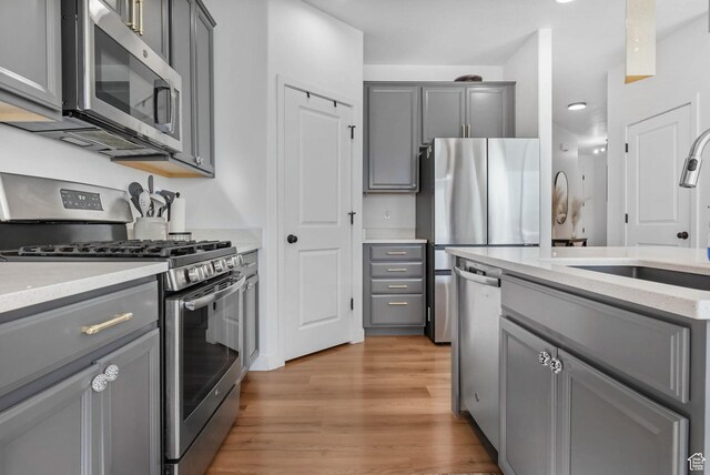 15223 S Wild Horse Way, Bluffdale, UT 84065 - kitchen with appliances with stainless steel finishes, gray cabinets, a sink, light wood finished floors, and light stone countertops
