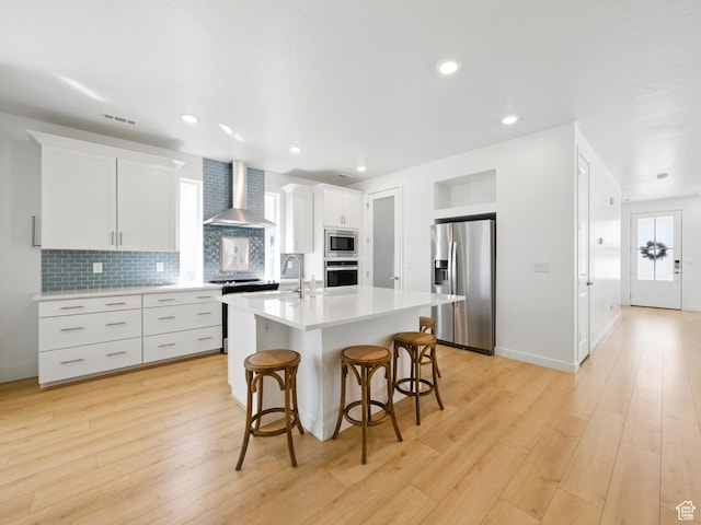 6034 W Sparrow View Dr, South Jordan, UT 84009 - kitchen featuring appliances with stainless steel finishes, wall chimney range hood, a kitchen bar, light countertops, and backsplash