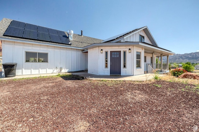 740 W Uzona Ave, Hildale, UT 84784 - back of house with board and batten siding, covered porch, roof mounted solar panels, a shingled roof, and brick siding
