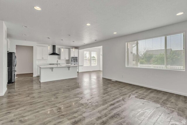 2199 W 650 S, Lehi, UT 84043 - unfurnished living room with a sink, baseboards, wood finished floors, recessed lighting, and a textured ceiling