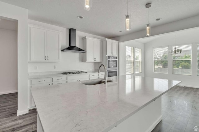 2199 W 650 S, Lehi, UT 84043 - kitchen with a sink, wall chimney exhaust hood, double oven, gas stovetop, and an island with sink