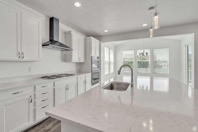 2199 W 650 S, Lehi, UT 84043 - kitchen featuring wall chimney range hood, a sink, a textured ceiling, stainless steel appliances, and white cabinets