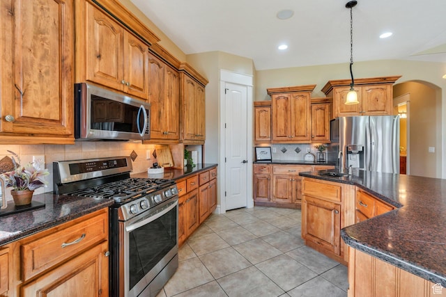 2632 S 2975 W, West Haven, UT 84401 - kitchen featuring stainless steel appliances, a sink, tasteful backsplash, arched walkways, and brown cabinets