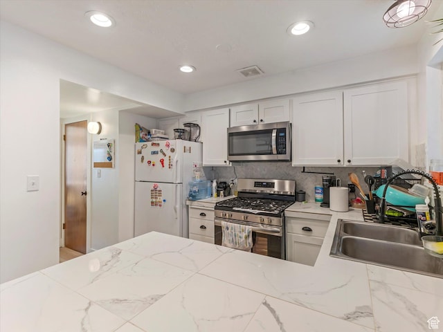 3951 S 875 E Unit 25, Ogden, UT 84403 - kitchen featuring stainless steel appliances, a sink, white cabinets, decorative backsplash, and light stone countertops