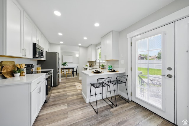 9604 S Stornoway Cir W, South Jordan, UT 84009 - kitchen with appliances with stainless steel finishes, a sink, light wood-type flooring, white cabinetry, and light countertops