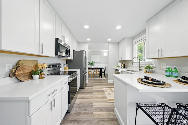 9604 S Stornoway Cir W, South Jordan, UT 84009 - kitchen with stainless steel appliances, a sink, light wood finished floors, recessed lighting, and white cabinets