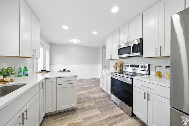 9604 S Stornoway Cir W, South Jordan, UT 84009 - kitchen featuring stainless steel appliances, wainscoting, light countertops, white cabinets, and light wood-style floors