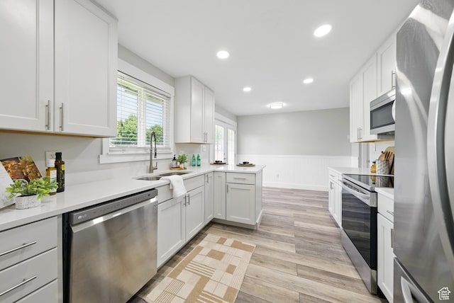 9604 S Stornoway Cir W, South Jordan, UT 84009 - kitchen featuring stainless steel appliances, a sink, a wainscoted wall, light countertops, and light wood-style floors