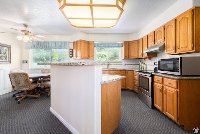 1478 N Ewe Turn St E, Kaysville, UT 84037 - kitchen featuring under cabinet range hood, stainless steel electric range, dark carpet, brown cabinetry, and a wainscoted wall