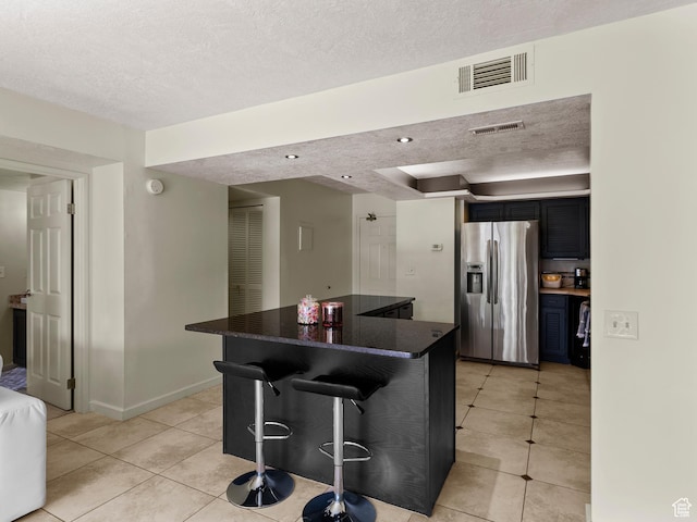105 S 1100 E Unit 508, Salt Lake City, UT 84102 - kitchen with stainless steel fridge with ice dispenser, light tile patterned floors, a kitchen breakfast bar, a textured ceiling, and a center island