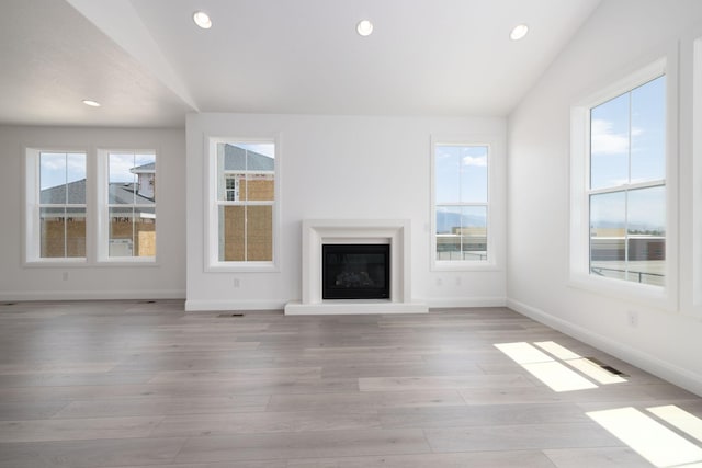 6527 W Barneys Creek Way, West Jordan, UT 84081 - unfurnished living room featuring baseboards, recessed lighting, light wood finished floors, and a glass covered fireplace