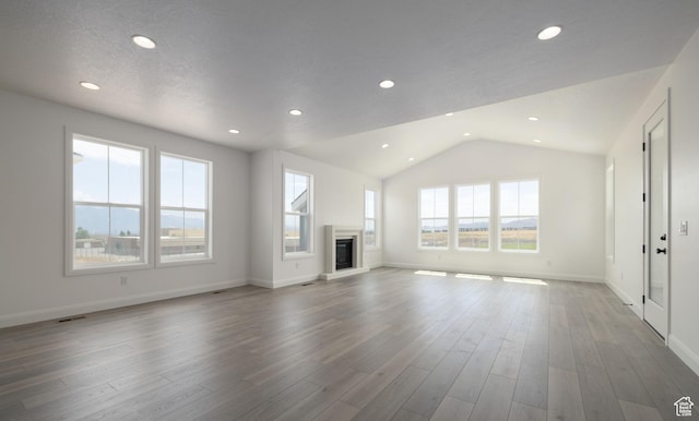 6527 W Barneys Creek Way, West Jordan, UT 84081 - unfurnished living room with lofted ceiling, a glass covered fireplace, baseboards, recessed lighting, and wood finished floors