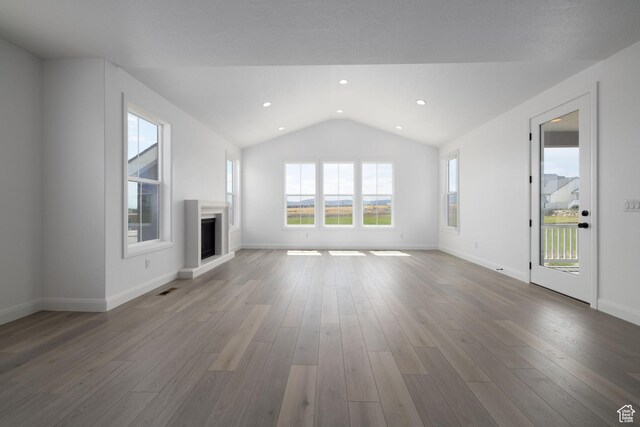 6527 W Barneys Creek Way, West Jordan, UT 84081 - unfurnished living room with a fireplace with raised hearth, vaulted ceiling, wood finished floors, baseboards, and recessed lighting