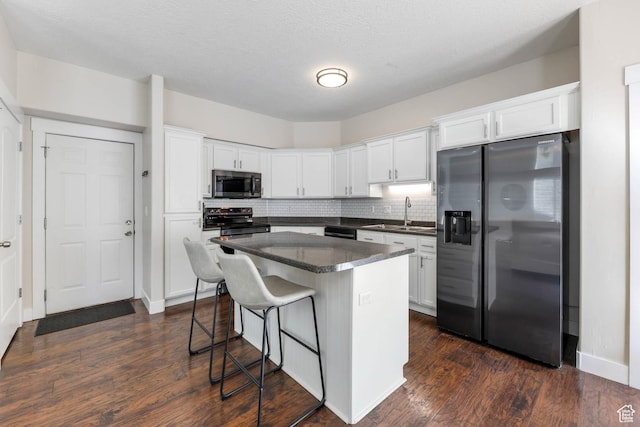 2671 N Garden Dr, Lehi, UT 84043 - kitchen featuring stainless steel appliances, a sink, dark countertops, a kitchen bar, and white cabinetry