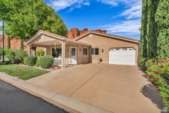 1050 W Red Hills Pkwy Unit 100A, Washington, UT 84780 - single story home featuring covered porch, an attached garage, driveway, stucco siding, and a tiled roof