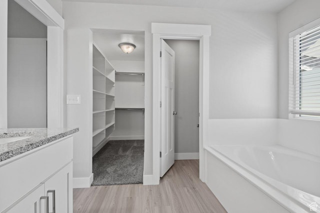 4972 N Sage Park Dr, Eagle Mountain, UT 84005 - bathroom featuring wood finished floors, a bath, vanity, a walk in closet, and baseboards