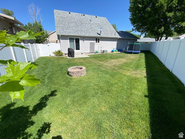 85 River Pointe Dr, Logan, UT 84321 - rear view of property with a fire pit, a trampoline, stucco siding, roof with shingles, and cooling unit