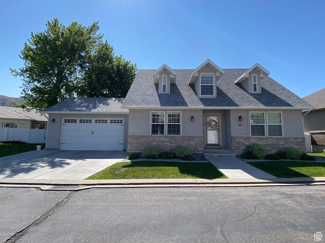 85 River Pointe Dr, Logan, UT 84321 - cape cod house with brick siding, stucco siding, an attached garage, and concrete driveway