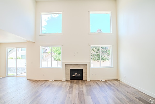 10926 S Little Sahara Dr Unit 1002, South Jordan, UT 84009 - unfurnished living room featuring a towering ceiling, light wood-style floors, a tile fireplace, and baseboards