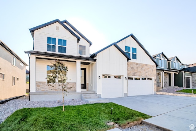 10926 S Little Sahara Dr Unit 1002, South Jordan, UT 84009 - view of front of house with a porch, board and batten siding, stone siding, driveway, and a garage