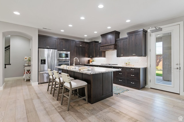 2914 E 1880 S, St George, UT 84790 - kitchen with stainless steel appliances, arched walkways, a kitchen breakfast bar, decorative backsplash, and light wood-style floors