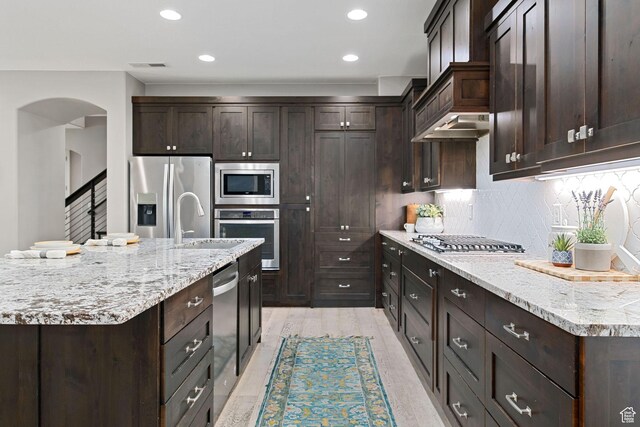 2914 E 1880 S, St George, UT 84790 - kitchen featuring appliances with stainless steel finishes, dark brown cabinets, arched walkways, tasteful backsplash, and a sink