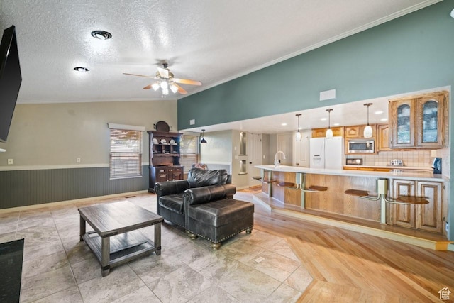 2045 W 5025 S, Roy, UT 84067 - living area with a ceiling fan, crown molding, lofted ceiling, a textured ceiling, and a wainscoted wall