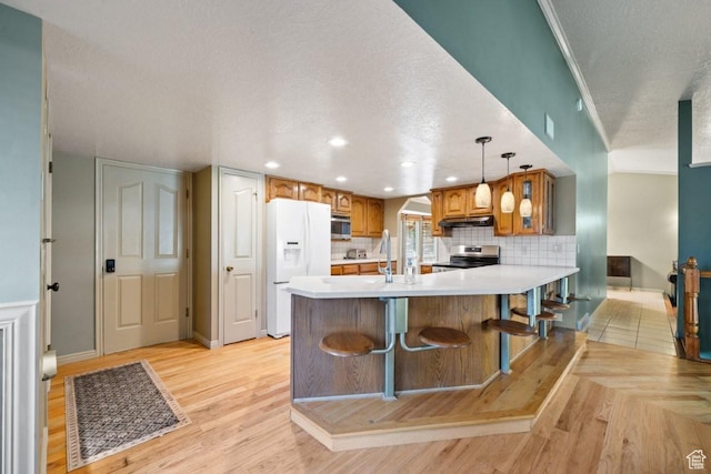 2045 W 5025 S, Roy, UT 84067 - kitchen with stainless steel appliances, a textured ceiling, light countertops, brown cabinetry, and under cabinet range hood