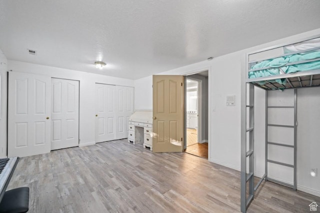 2045 W 5025 S, Roy, UT 84067 - unfurnished bedroom with two closets, light wood-style flooring, and a textured ceiling