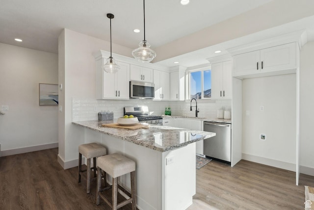 345 E 100 S, Santaquin, UT 84655 - kitchen featuring appliances with stainless steel finishes, a peninsula, light stone counters, light wood-type flooring, and recessed lighting