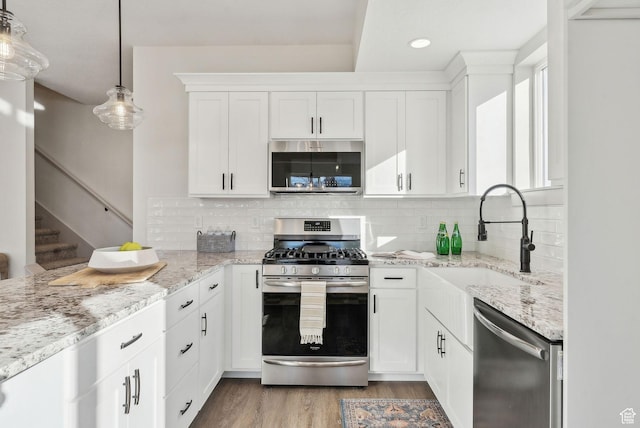 345 E 100 S, Santaquin, UT 84655 - kitchen with stainless steel appliances, a sink, white cabinets, light wood-type flooring, and light stone countertops