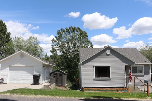 484 N Main St, Malad City, ID 83252 - view of front of property featuring a shingled roof, an outdoor structure, a garage, driveway, and a front yard